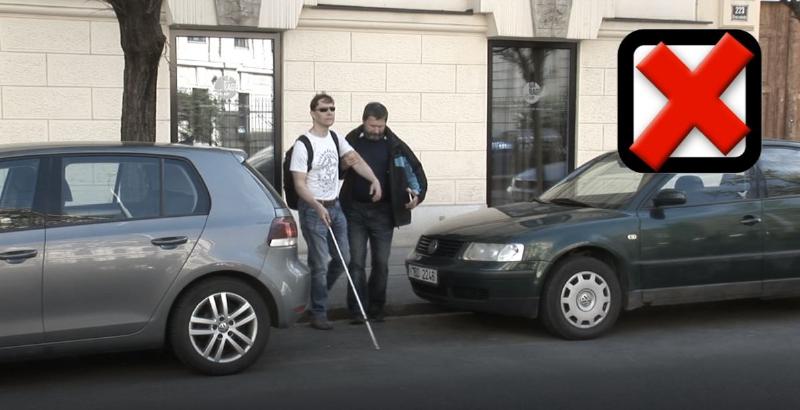 Ukázka nevhodného způsobu pomoci převedení člověka se zrakovým postižením přes silnici