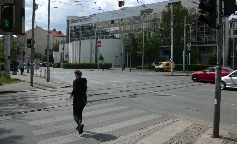 Nevidomá osoba přechází vozovku na zelenou.