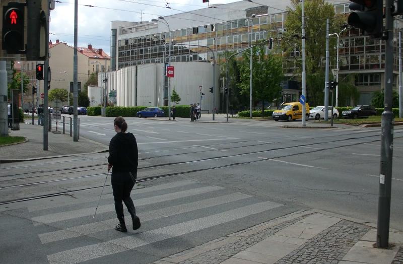 Nevidomá osoba přechází vozovku na červenou.